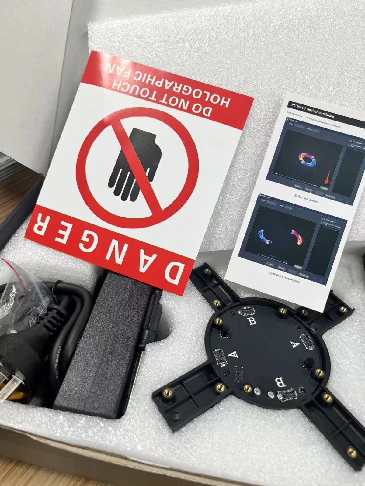 Holographic fan kit with wiring, warning sign, and setup instructions inside the box