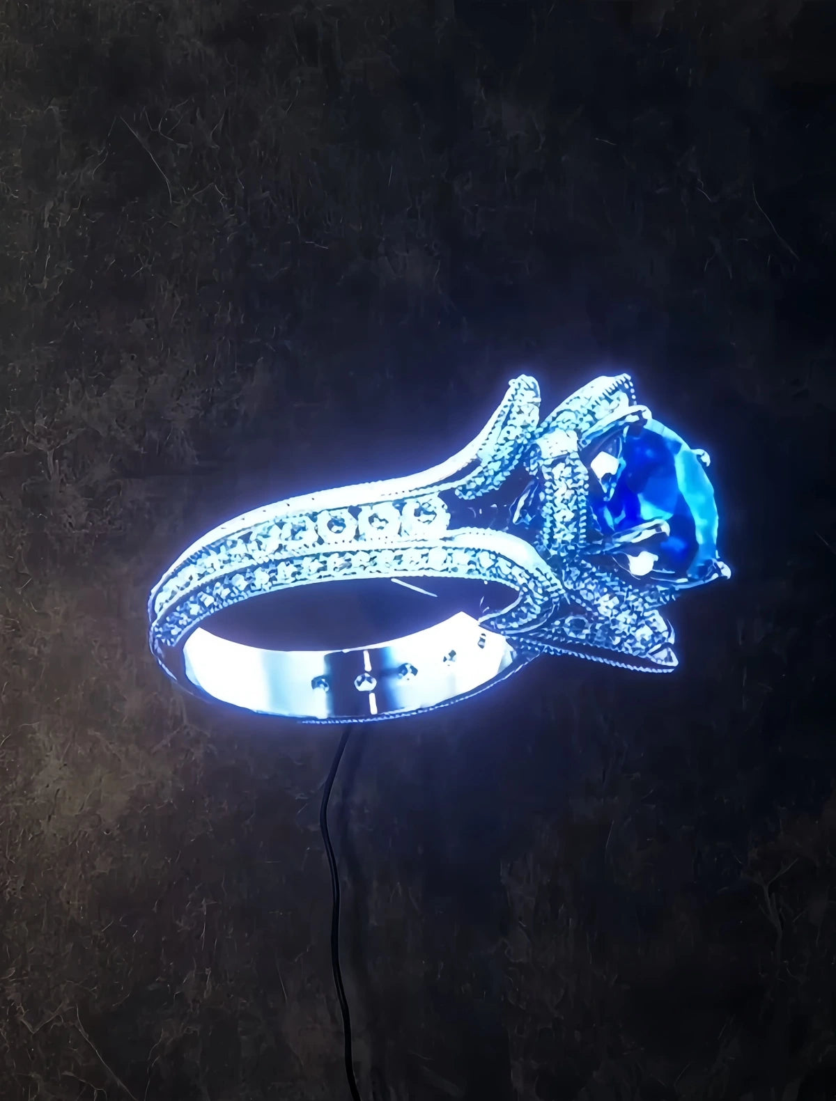 Holographic ring with a blue gemstone on a dark background