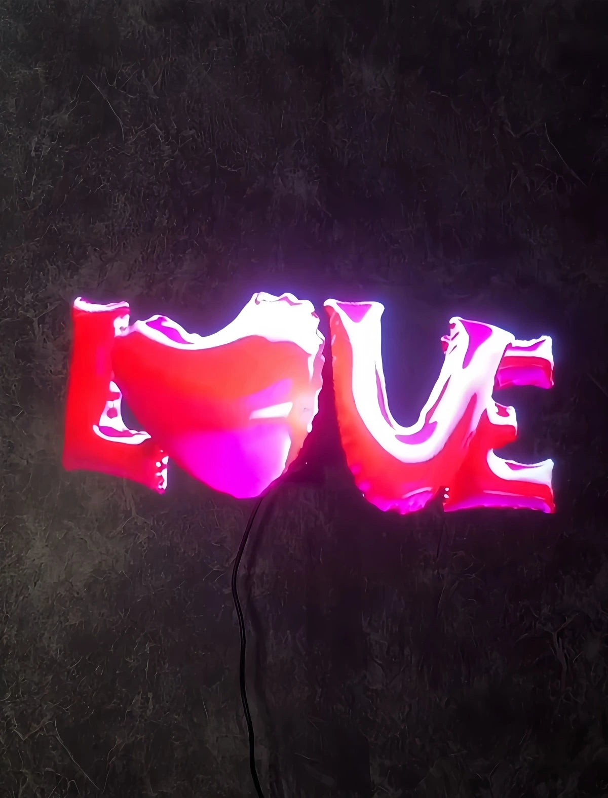 Holographic neon-style “LOVE” sign on a dark wall