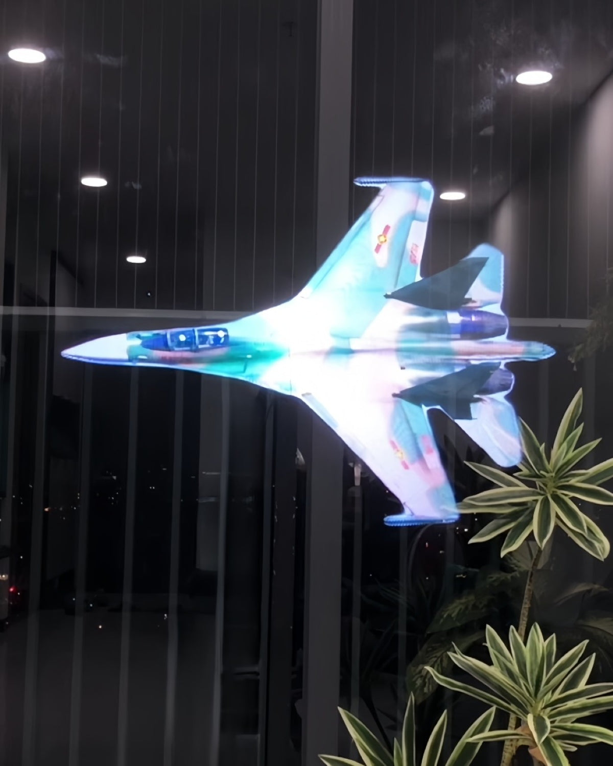 Holographic 3D fighter jet projection in a dim indoor setting.
