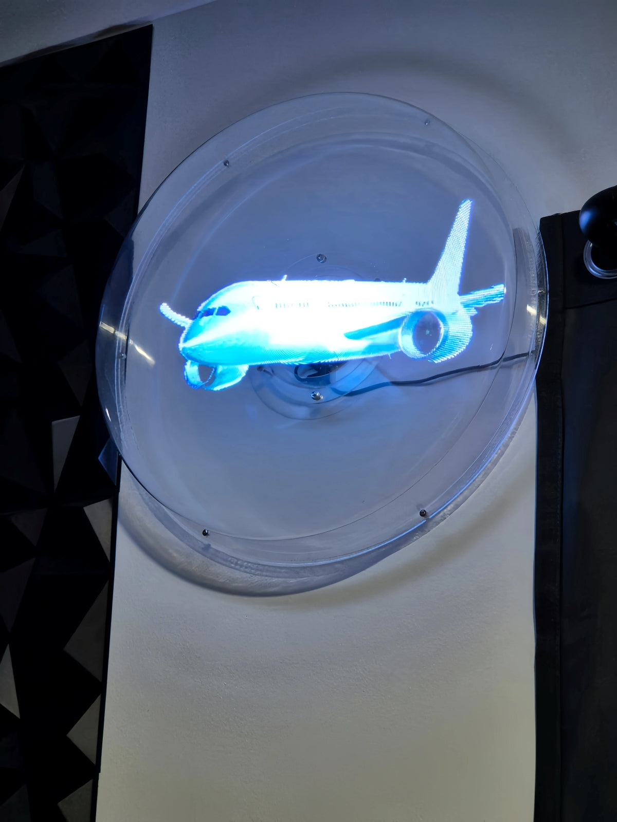 Hologram display showing a glowing 3D airplane inside a clear protective cover